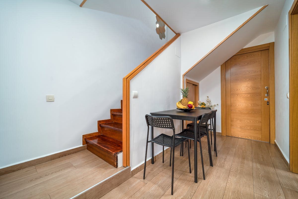 White under-stairs storage with drawers and a tall cupboard door, fitted beneath a wooden staircase in a hallway