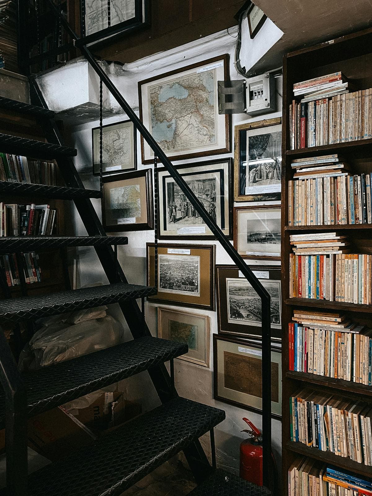 Real packed bookcase reaching the stair landing — sized and built for a working library, used as bookcase inspiration.